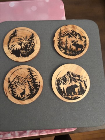 Four handmade wooden coasters with wildlife burned into them: a bald eagle, a moose, a deer and a bear